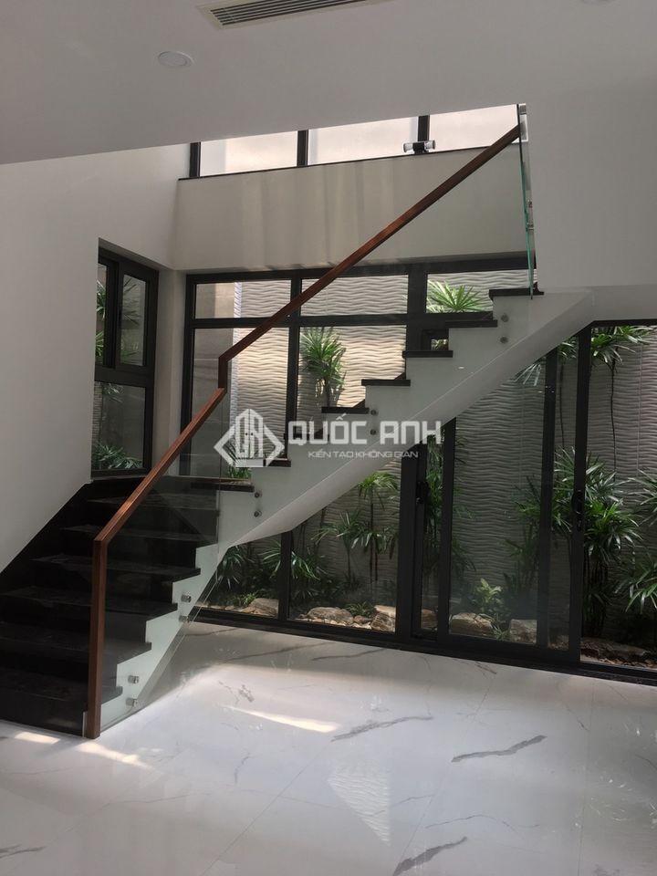 Cầu thang kính tay vịn gỗ trong không gian hiện đại. 