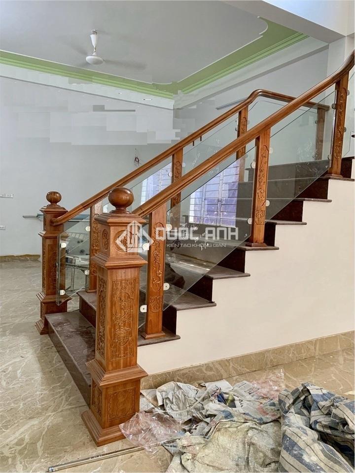 Cầu thang kính tay vịn gỗ căm xe có vẻ đẹp sang trọng, ấn tượng.